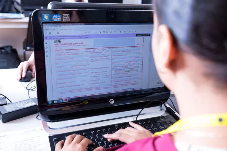 a person working at a computer doing medical billing and coding.