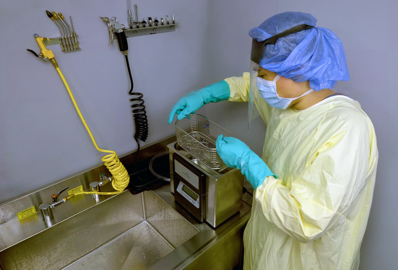 Central service processing technician sterilizing medical equipment in a healthcare facility.