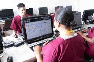 two students at computers, each working on medical billing and coding projects